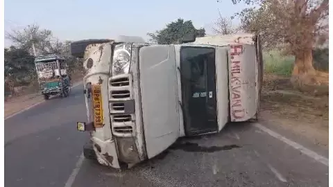 सड़क के बीचो बीच पलटा दूध से भरा वाहन।