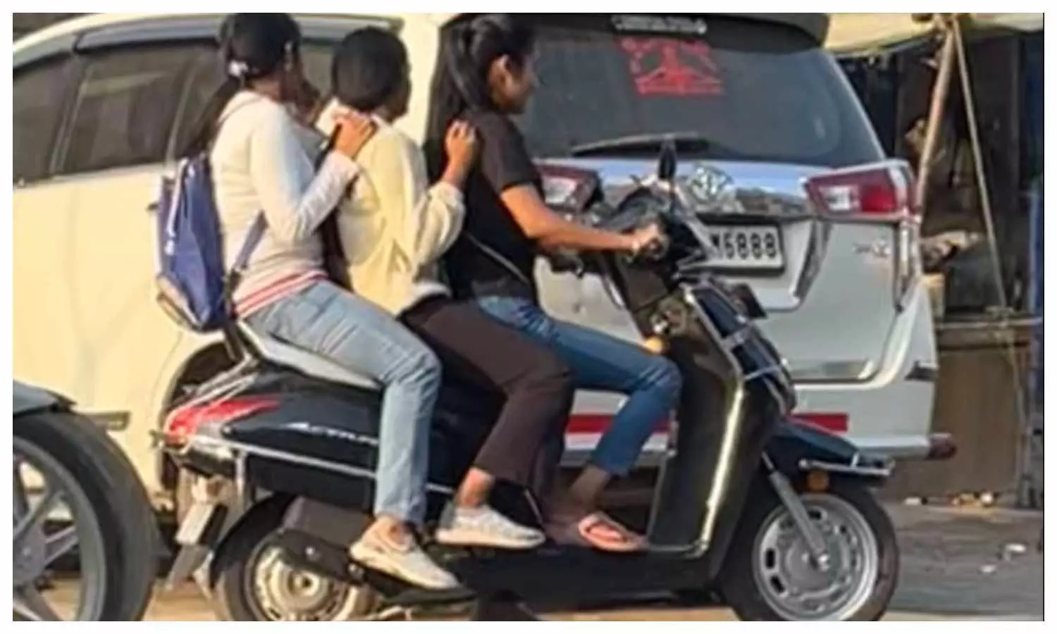 तीन सवारी के साथ बिना हेलमेट के सफर करती युवतियां।