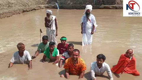 Lakhimpur News: सरयू घाट बंद होने पर कांवड़ियों का विरोध, प्रशासन के बनाए तालाब में बैठकर किया धरना